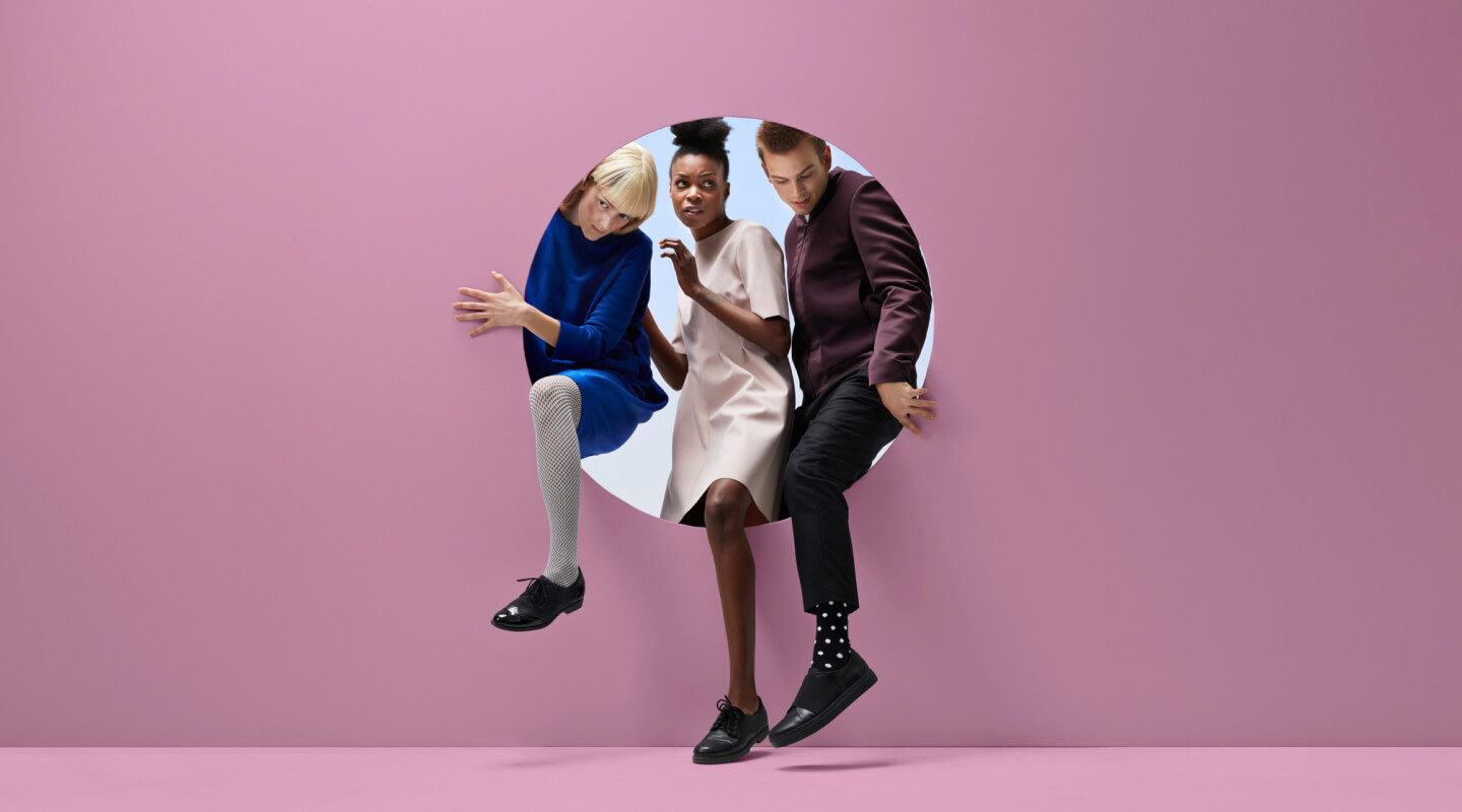 three people climb through a circle in a pink wall