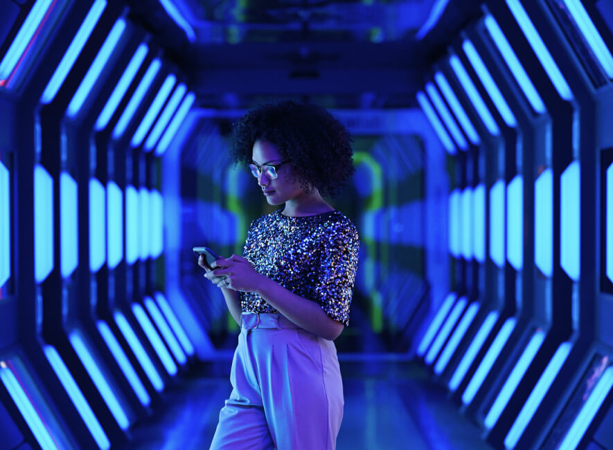 Woman standing in blue light looking at her cell phone